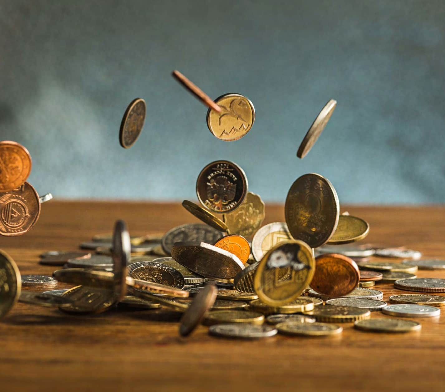 Coins falling and scattering on wooden surface.