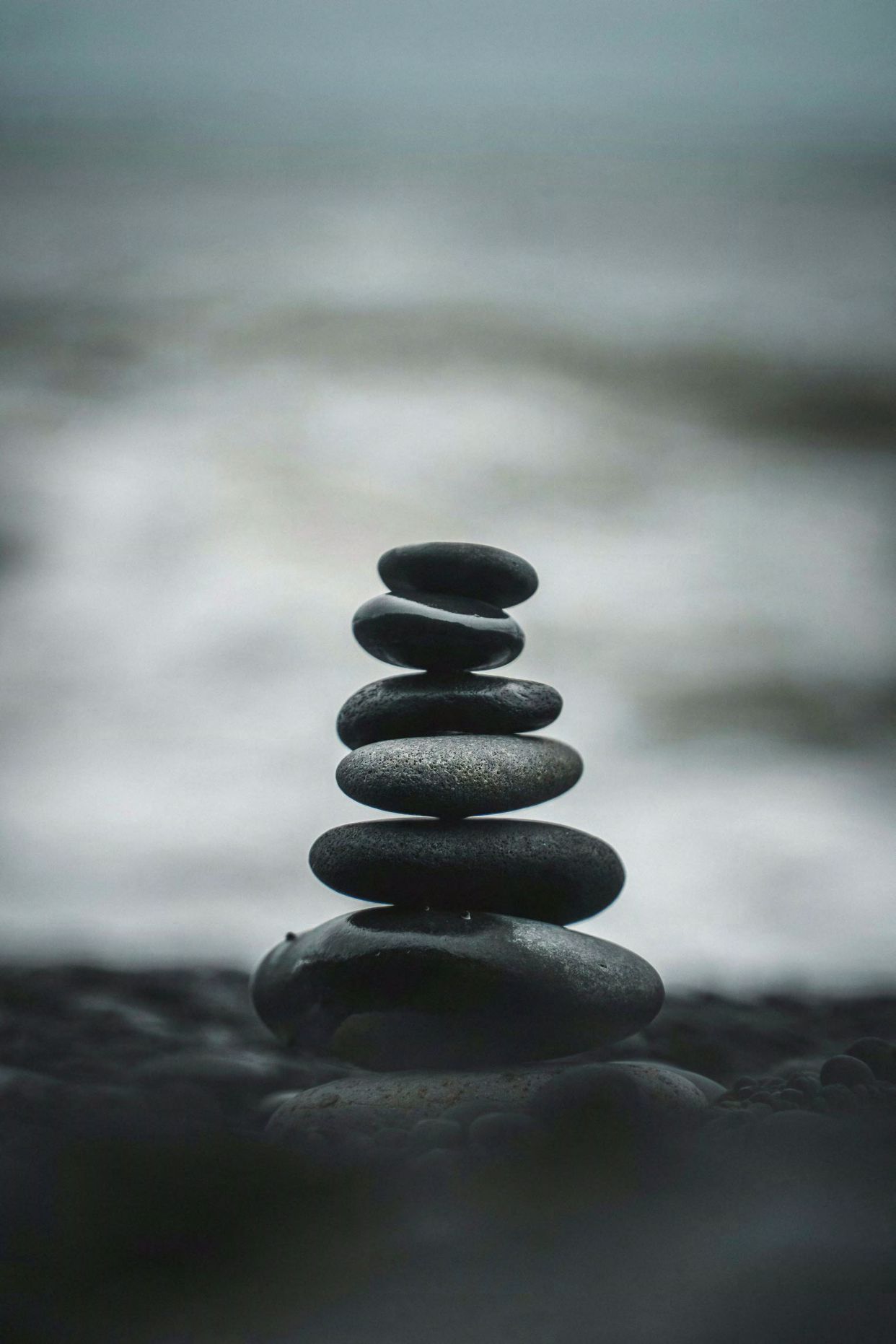 Stacked stones on beach with ocean background.