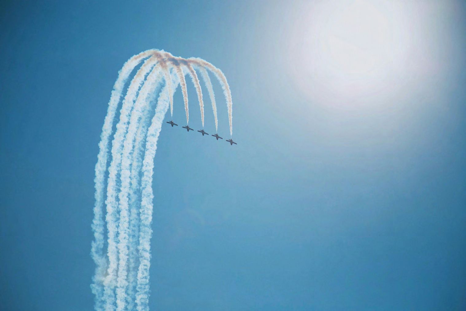 Airshow planes releasing white smoke in formation.