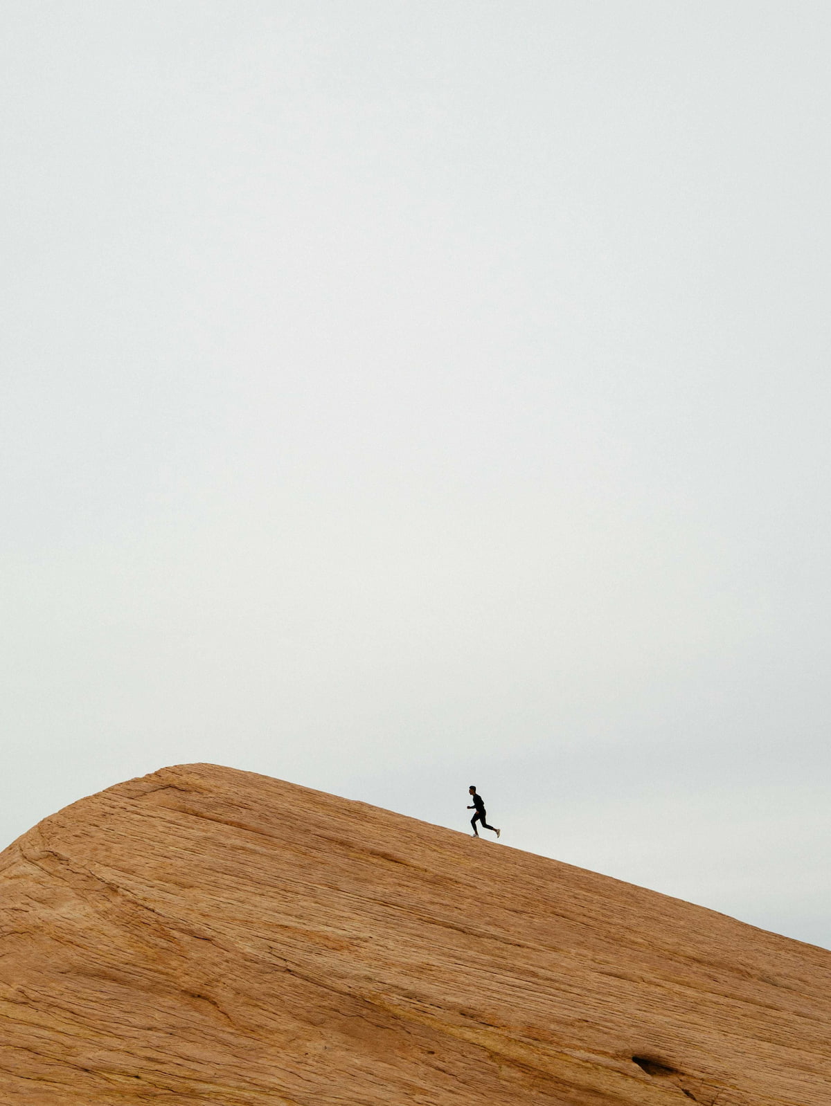 Person jogging up a large rock formation.