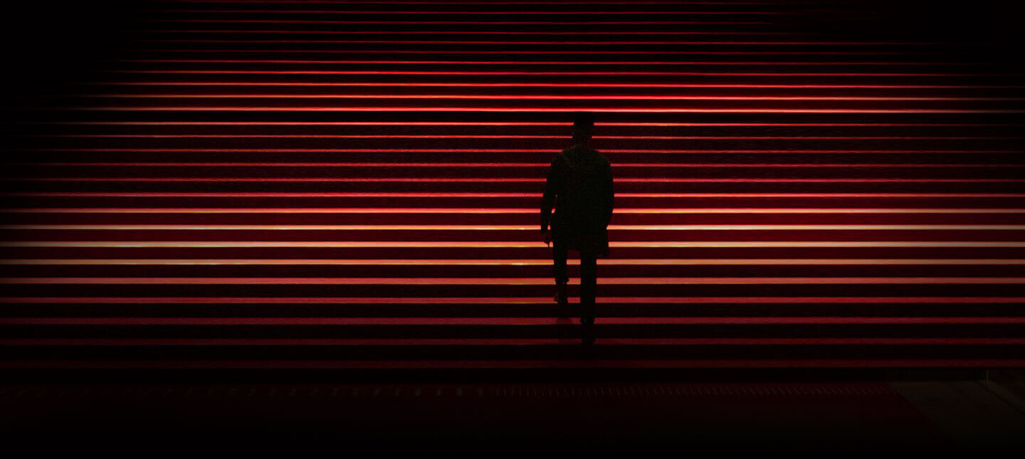 Silhouette walking up red-lit stairs